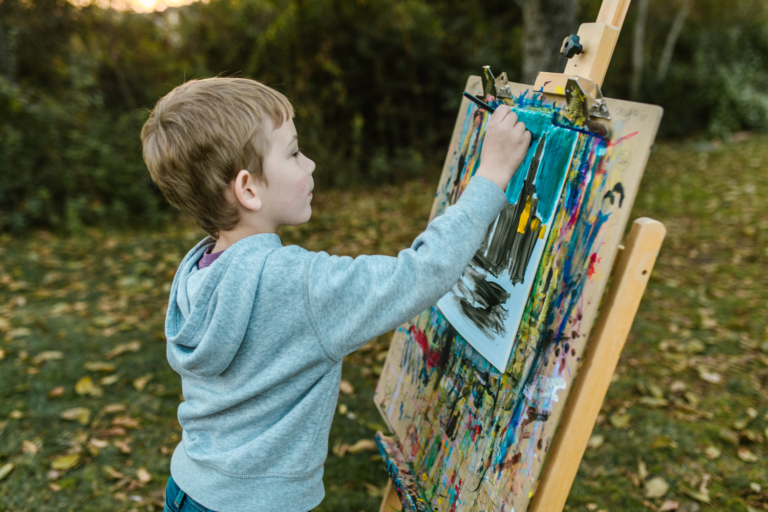 a-young-boy-painting-outdoors