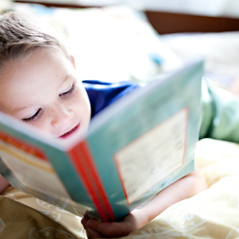 Un giovane ragazzo che sorride leggendo un libro